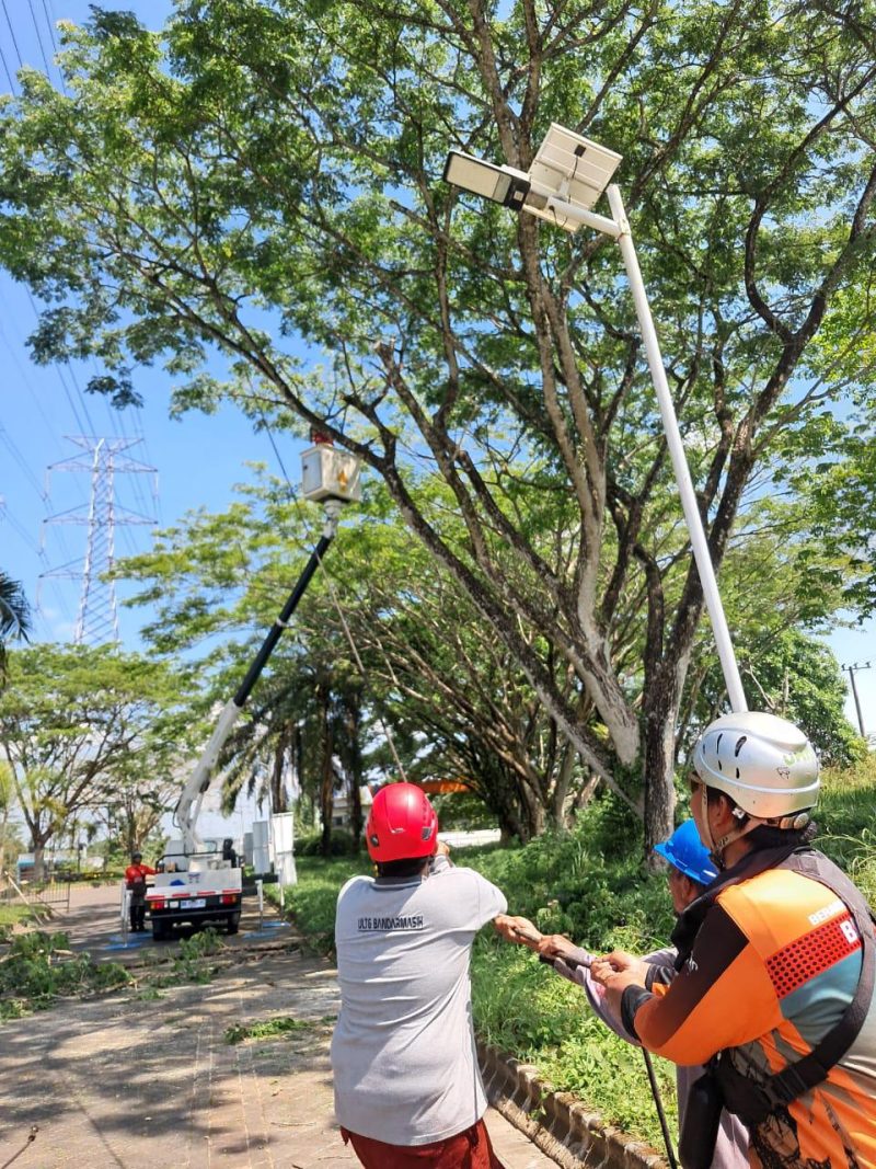 Dengan penuh kewaspadaan, tim pemeliharaan PLN ULTG Banjar menarik dahan pohon besar yang menjulang dekat jaringan transmisi saat melakukan pemangkasan. Di tengah terik matahari, semangat gotong royong membara demi memastikan listrik tetap andal mengalir di momen jelang Hari Kemerdekaan.