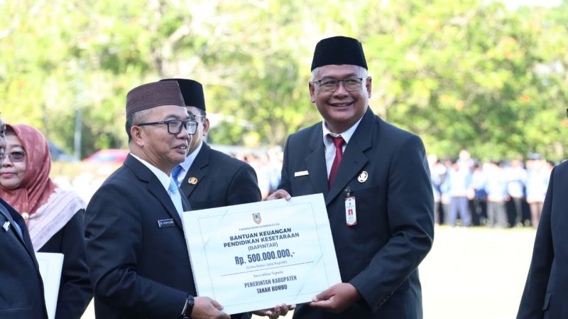 Sekretaris Daerah Provinsi, Muhammad Syarifuddin kepada Bupati Tanah Bumbu Andi Rudi Latif melalui Staf Ahli Bupati Bidang Ekonomi, Keuangan, dan Pembangunan, Andrianto Wicaksono menerima bantuan keyangan saat peringatan Hari Otonomi Daerah dan Hari Pendidikan Nasional. (Foto: Istimewa)